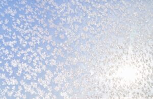 Abstract winter background. Frost on a frozen window against the blue sky. High quality photo