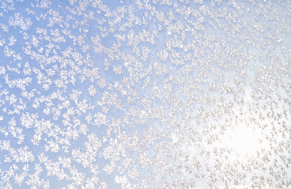 Abstract winter background. Frost on a frozen window against the blue sky. High quality photo