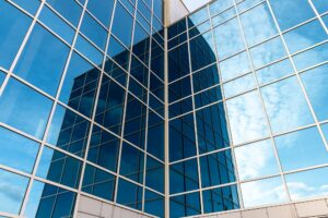 Glass building with mirrored windows. Skyscraper. Line pattern, perspective, steel structure, urban abstraction. Geometric shape, modern exterior, wall texture.