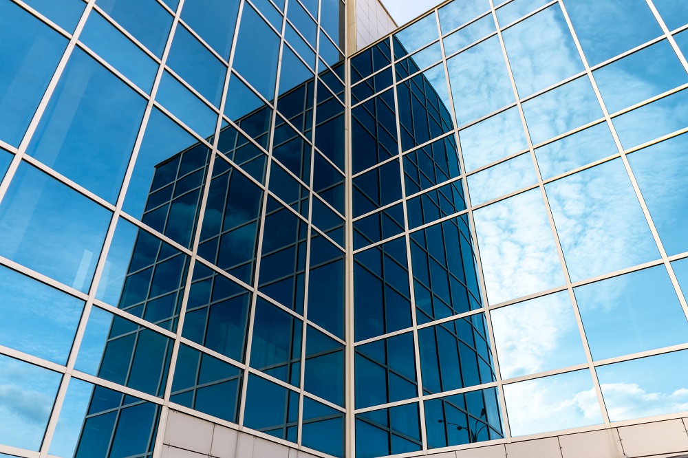 Glass building with mirrored windows. Skyscraper. Line pattern, perspective, steel structure, urban abstraction. Geometric shape, modern exterior, wall texture.